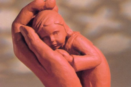 Ton-Figur: eine Hand hält tröstend ein Kind.