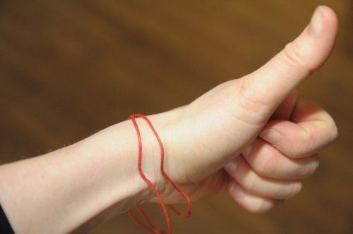 Commitment: Jede und jeder schneidet für sich einen Teil des roten Prozess-Fadens ab - und bindet sich den Faden ums Handgelenk.