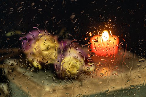 Kerze hinter regennassem Fensterglas