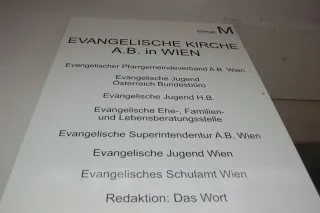Info-Schild an der Hauswand über die verschiedenen Arbeitsbereiche und Einrichtungen.