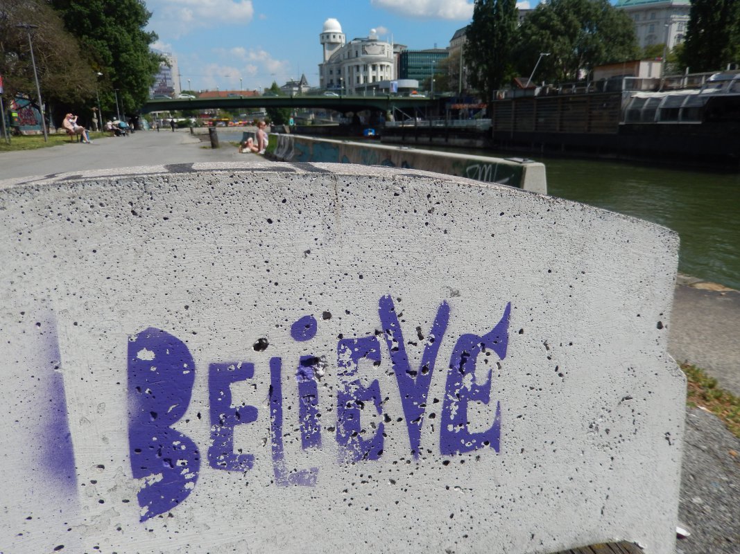 Graffiti des Wortes &quot;Believe&quot; - im Hintergrund der Donaukanal